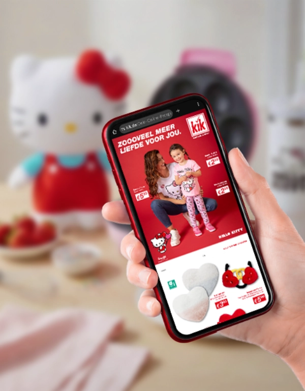 Hand houdt smartphone met Hello Kitty reclame, roze wafelijzer en snacks op tafel