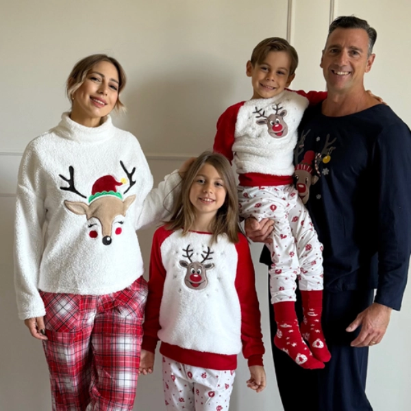 Een gezin gekleed in feestelijke kersttruien en pyjama's poseert samen en laat seizoensgebonden ontwerpen van rendieren en sneeuwvlokken zien.