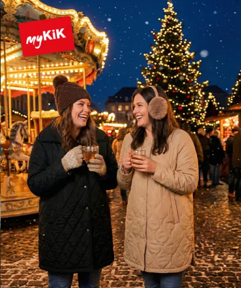 Ein gemütlicher Weihnachtsgeschenkkorb mit einem Plüschrentier, flauschigen Decken, einem Bärenbecher, heißer Schokoladenmischung und goldenen Ornamenten.