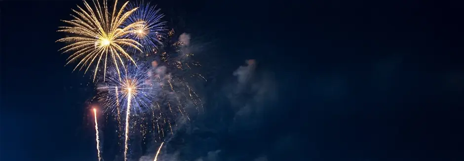 KiK wenst je een gelukkig nieuwjaar! Levendig vuurwerk explodeert in een donkere nachtelijke hemel en laat uitbarstingen van geel, blauw en wit zien, die de wolken eromheen verlichten.