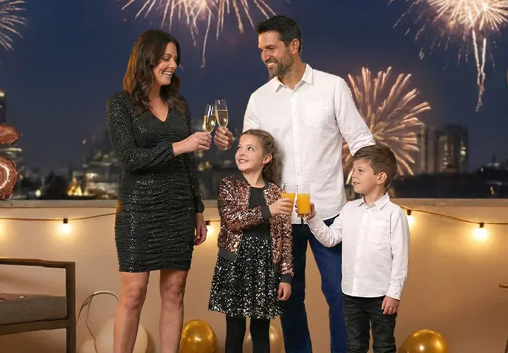 Een gezin viert feest met drankjes op een balkon, terwijl vuurwerk de nachtelijke hemel achter hen verlicht. Een gezin viert feest met drankjes op een balkon, terwijl vuurwerk de nachtelijke hemel achter hen verlicht.