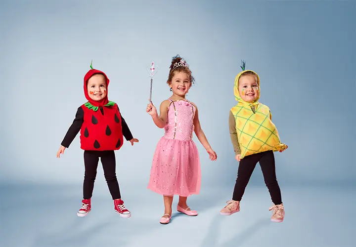 Drie kinderen in grappige fruitkostuums: aardbei, ananas en een prinses in een roze jurk