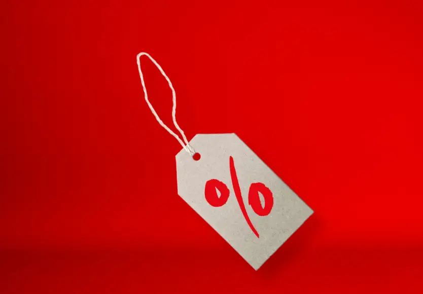 Een grijs prijskaartje met een rood procentteken op een felrode achtergrond, dat kortingen of aanbiedingen symboliseert.