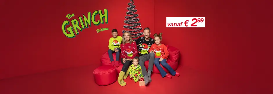 Een gezin gekleed in kleurrijke kersttruien poseert op rode zitzakken voor een feestelijke boom tegen een bijpassende rode achtergrond.