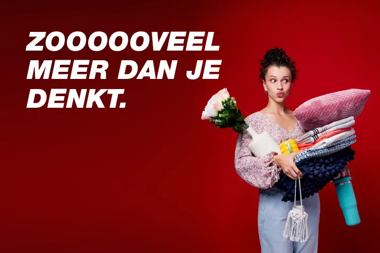 Een persoon houdt meerdere kleurrijke voorwerpen vast, waaronder dekens, een waterfles en bloemen, tegen een levendige rode achtergrond.