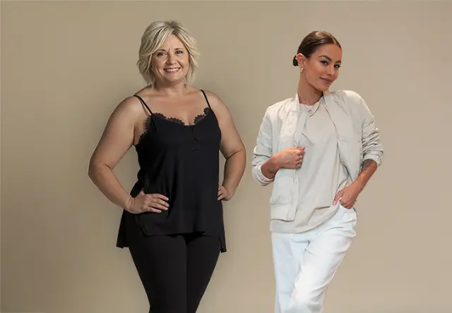 Twee vrouwen staan naast elkaar, de een in een zwart topje en legging, de ander in een licht jasje en broek, tegen een neutrale achtergrond.