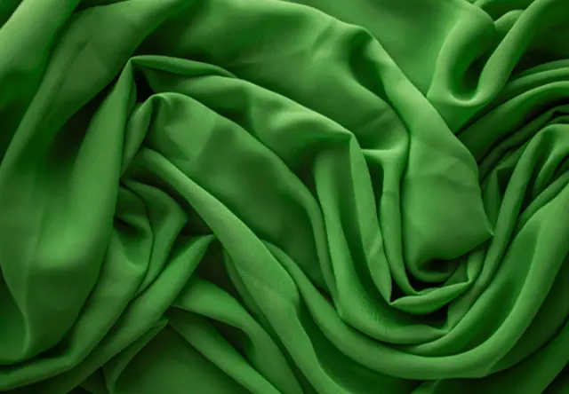 Groene stof met vloeiende textuur Groene stof met zachte plooien en vloeiende structuur – gedetailleerd textieloppervlak in krachtige kleur