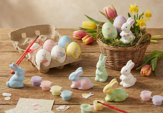 Kleurrijke papieren konijnen en een roze keramisch konijn tussen bloeiende bloemen en decoratieve vazen in een levendige lentetuin.