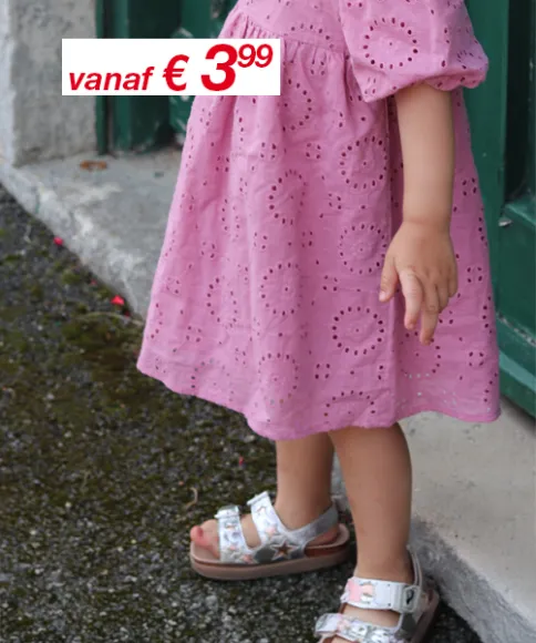 Een jongen in een gestreepte outfit en een meisje in een gebloemde jurk houden elkaars hand vast, beide glimlachend, tegen een effen witte achtergrond.