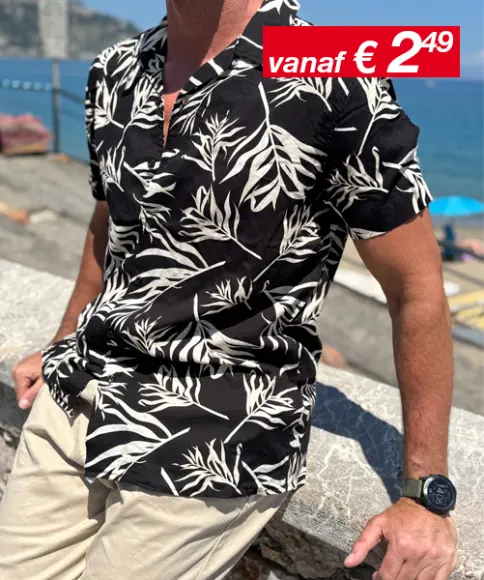 Een man in een nonchalante houding, gekleed in een groen T-shirt en lichtblauwe korte broek, met zwarte sportschoenen, voor een zachte achtergrond.