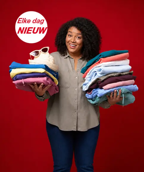 Een vrouw houdt verschillende stapels opgevouwen kleding vast tegen een rode achtergrond - de nieuwste modetrends voor dames en heren