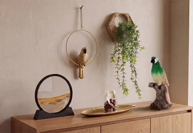  Decoratieve woonaccessoires met papegaaienfiguren, wanddecoratie en hangplant op een houten dressoir in junglestijl