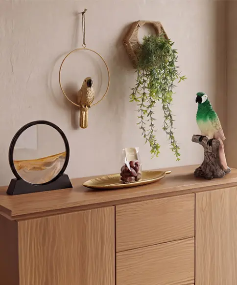  Decoratieve woonaccessoires met papegaaienfiguren, wanddecoratie en hangplant op een houten dressoir in junglestijl
