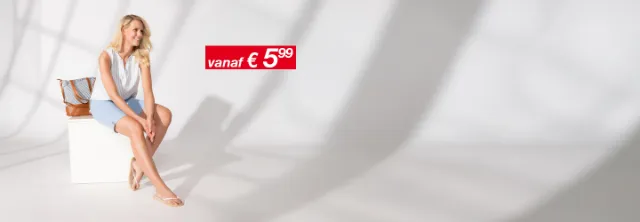 Een vrouw draagt een lichte, zomerse blouse met een jeansshort en lacht blij.