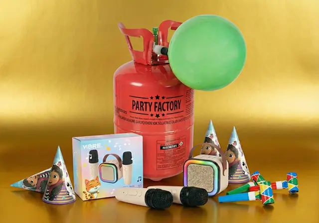 Een kleurrijke feestopstelling met een gastank, een groene ballon, feesthoedjes, speelgoedmicrofoons en een muziekdoos op een gouden achtergrond.