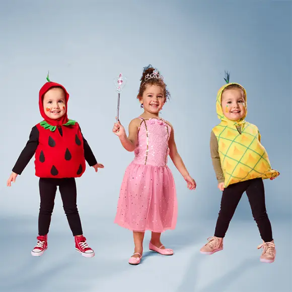 Drie kinderen in grappige fruitkostuums: aardbei, ananas en een prinses in een roze jurk