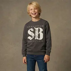 Jongen in een grijze sweatshirt en jeans lacht voor een neutrale achtergrond.