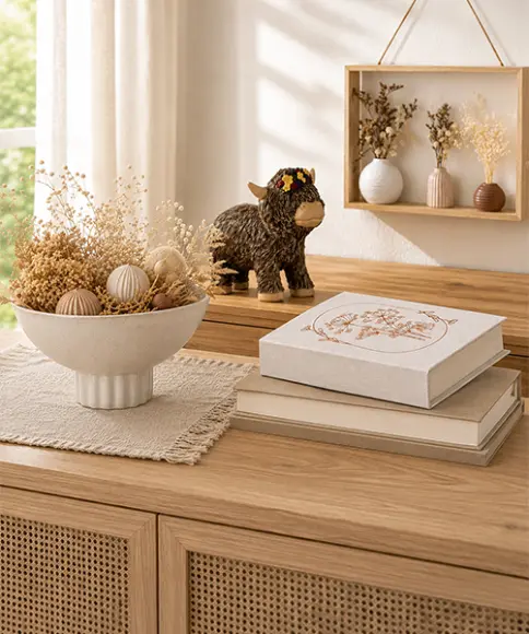 Decoratieve woonaccessoires van natuurlijke materialen op een houten dressoir – droogbloemen, schaal en dierenfiguur in een natuurlijke woonstijl