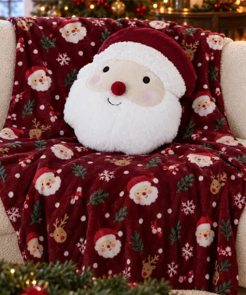 Knusse rode kerstdeken met kerstman- en rendiermotieven en een rond kerstmannenkussen op de bank