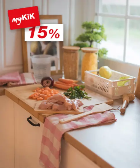 Een licht aanrecht met kipfilet, gehakte wortels, kruiden en verschillende ingrediënten in potjes, klaar om te koken.