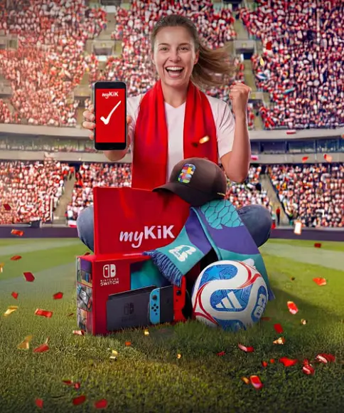 Een persoon in een stadion houdt een smartphone met de myKiK‑app vast, omringd door een Nintendo Switch, een voetbal, een pet, een sjaal en een myKiK‑pakket.