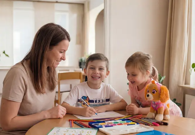 Een vrouw tekent samen met twee kinderen aan tafel. Kleurpotloden, waterverf en een PAW Patrol-knuffel zorgen voor volop creatief plezier. Een vrouw tekent samen met twee kinderen aan tafel. Kleurpotloden, waterverf en een PAW Patrol-knuffel zorgen voor volop creatief plezier.