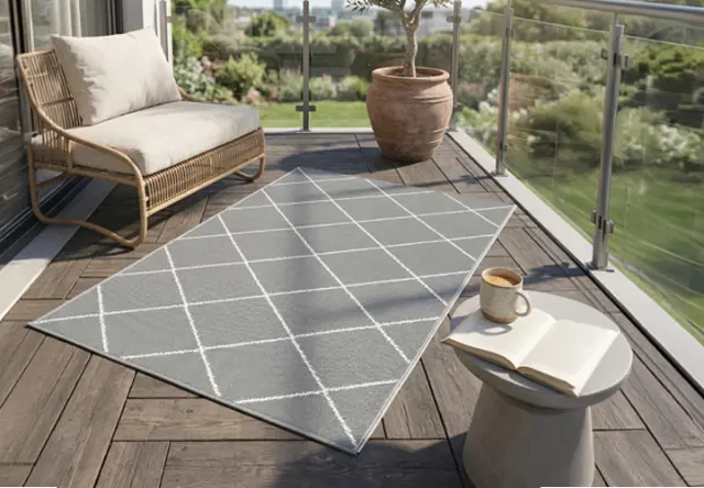 Moderne grijze buitentapijt met geometrisch patroon op een zonnig balkon met loungestoel en planten – zorgt voor comfort en een stijlvolle sfeer buiten