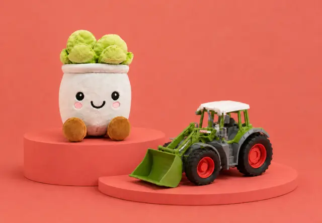 Een glimlachend pluchen plantje met groene bladeren en bruine voetjes staat naast een groene en rode speelgoedtractor op oranje ronde podiums.
