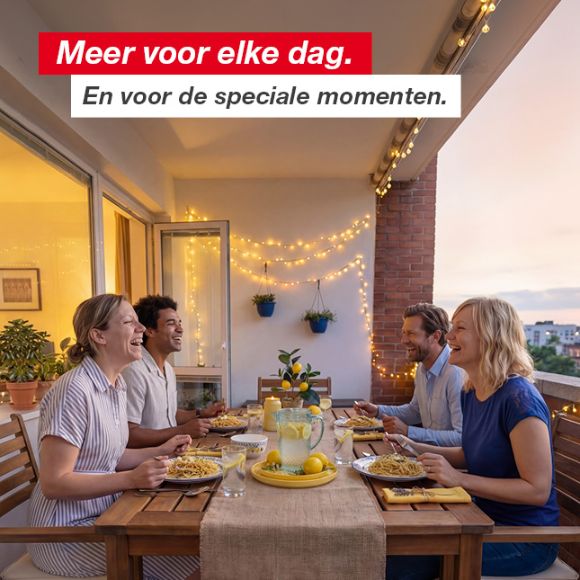 Vier personen genieten van een avondmaaltijd met pasta en limonade op een sfeervol versierd balkon met lichtsnoeren en potplanten.