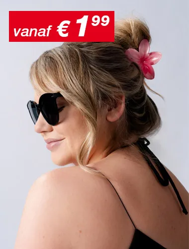 Een vrouw met golvend haar gestyled in een knot versierd met een roze bloem, draagt een zwart topje en poseert van achteren tegen een lichte achtergrond.