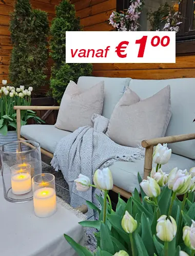 Gezellig buiten zitten met zachte kussens, een gebreid kleed, gloeiende kaarsen en bloeiende tulpen tegen een houten achtergrond.