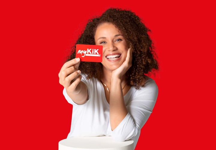 Persoon met krullend haar houdt een rode myKik kaart vast voor een rode achtergrond.
