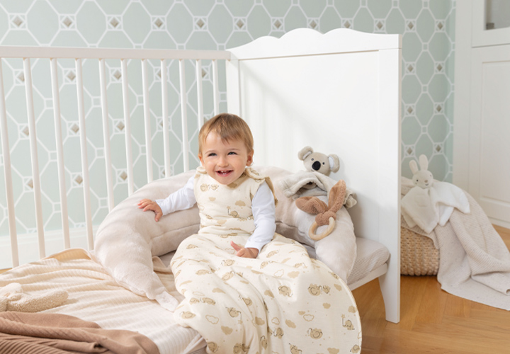 Een peuter in een knusse slaapzak zit comfortabel in een kinderkamer met pluchen speelgoed. Een peuter in een knusse slaapzak zit comfortabel in een kinderkamer met pluchen speelgoed.