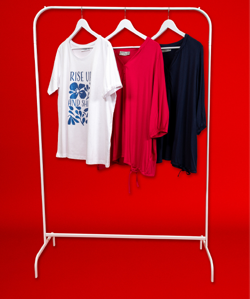 Drie stijlvolle shirts op een wit kledingrek: een wit T-shirt met print, een roze blouse en een marineblauwe top tegen een felrode achtergrond.