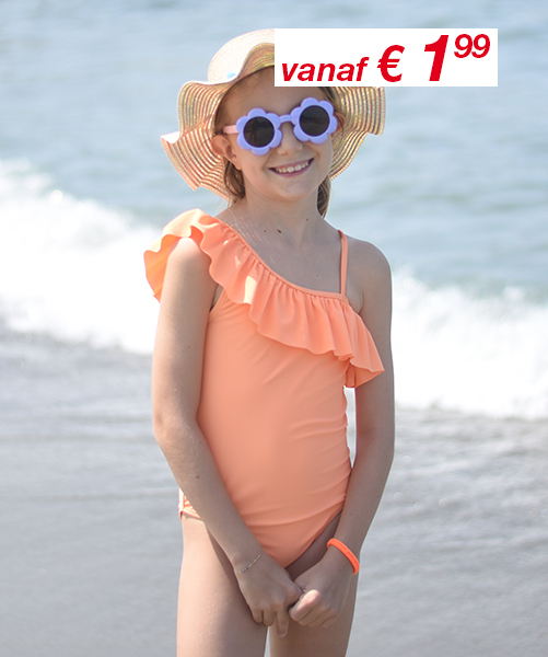Een kind in een koraalkleurig one-shoulder badpak met ruches staat op het strand en draagt een strohoed met brede rand. Een prijskaartje is zichtbaar.