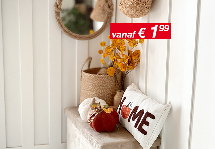 Gezellige wooncultuur met een ronde spiegel, gevlochten manden, herfstbladeren en een decoratief kussen met het opschrift ‘HOME’ en een pompoenaccent